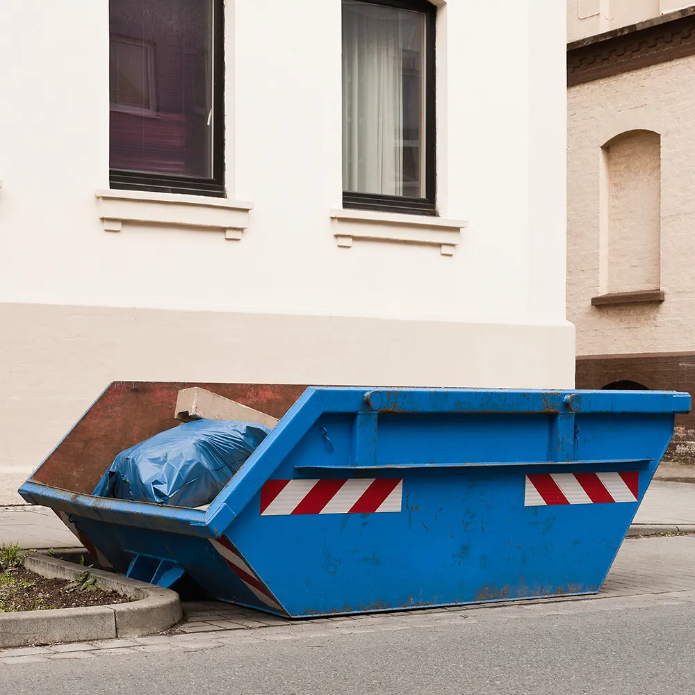 Ein blauer Container für Abfall steht vor einem Wohnhaus